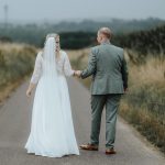 Frisch vermähltes Ehepaar schießt Hochzeitsfotos auf einer Wiese mit hohem Gras 