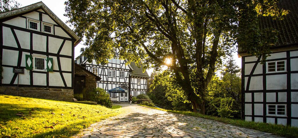 Hochzeitslocation in NRW, Kürten drei alte scheunenhäuser umgeben von strahlend grünen bäumen