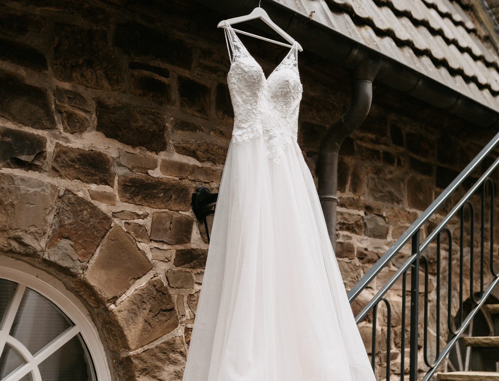 weißes Brautkleid mit V-Ausschnitt hängt an einer Hauswand
