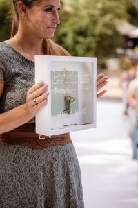 Traurednerin Elena Böcker hält eine kleine Glasbox in der Hand in welcher zwei Schlüssel drinnen aufgehangen sind
