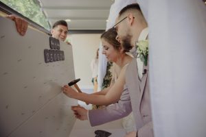 Ehepaar hämmert beschriftete Schiefern an eine Wand mit ihren Eheversprechen