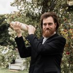 Bräutigam mixt während der Trauzeremonie Cocktails für die Hochzeitsgesellschaft