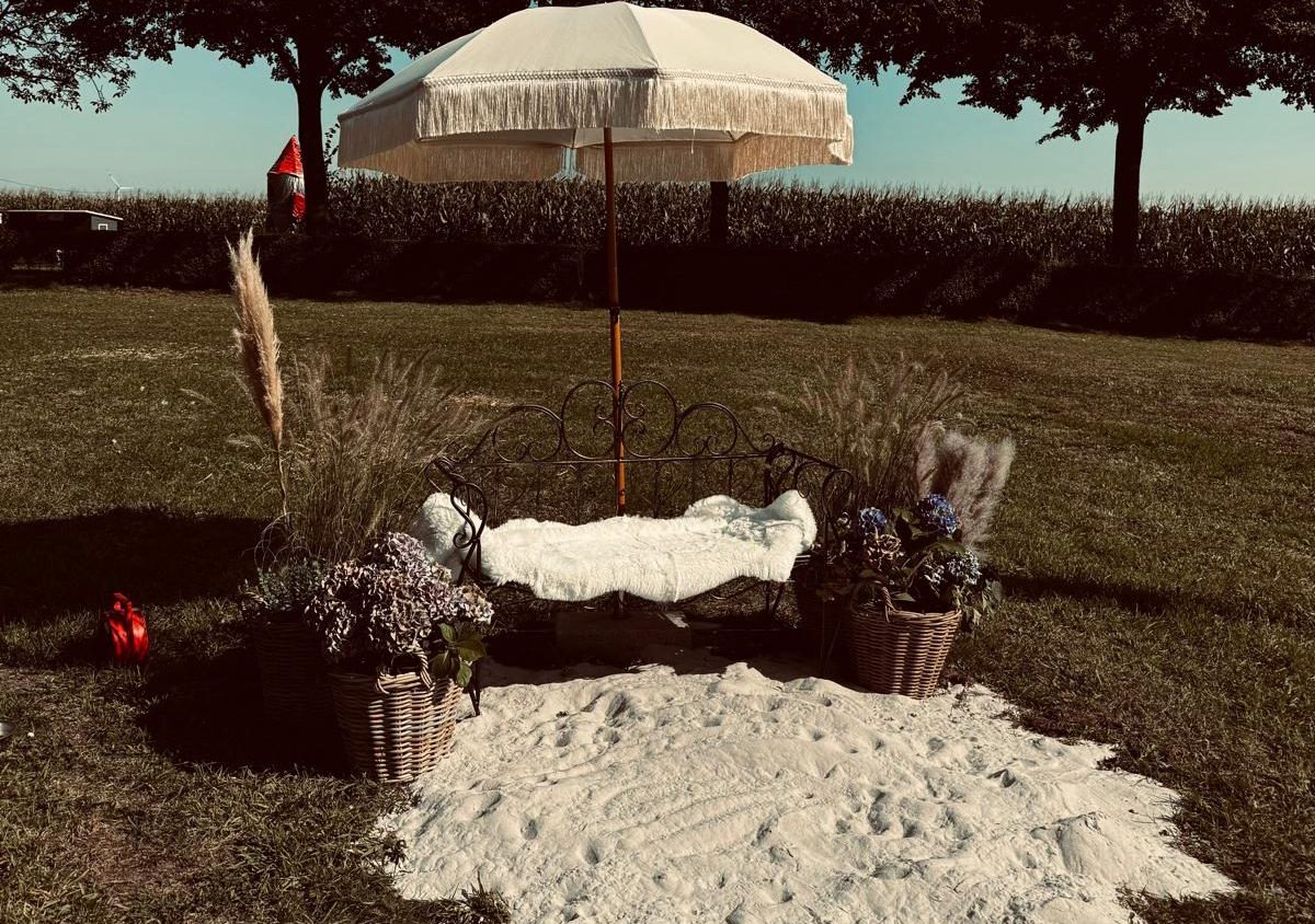 gemütliche Sitzecke, welche ebenfalls als Fotoecke dienen kann. Kleiner Sonnenschirm über einer schwarzenmetallsitzbank am Trauort