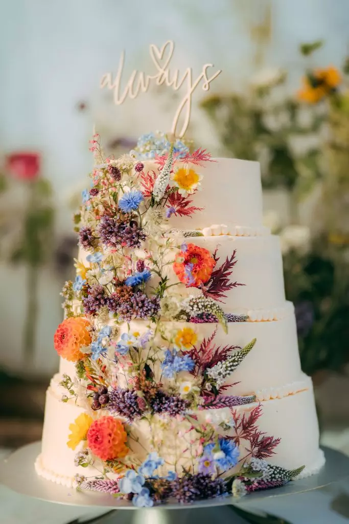 Hochzeitstorte mit bunten Blumen bei einer DIY-Hochzeit auf dem Bauernhof
